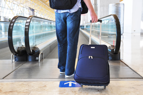  homme tirant bagages escalator à l'aéroport