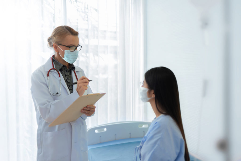 une jeune femme portant un masque qui parle aux docteurs