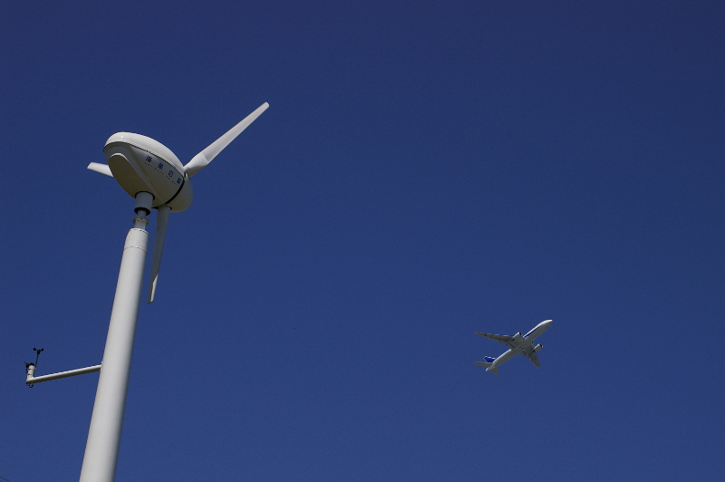 Windmill with airplane flying directly above.