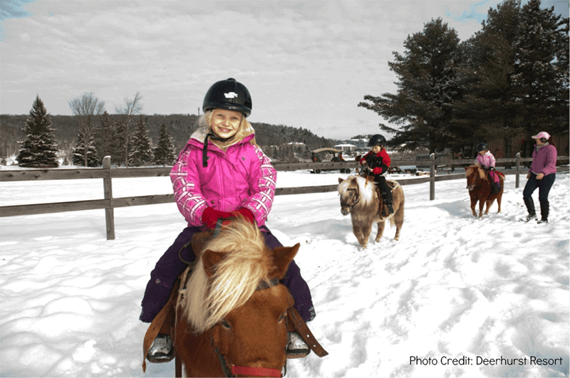 Children riding ponies in the snow at Deerhurst Resort