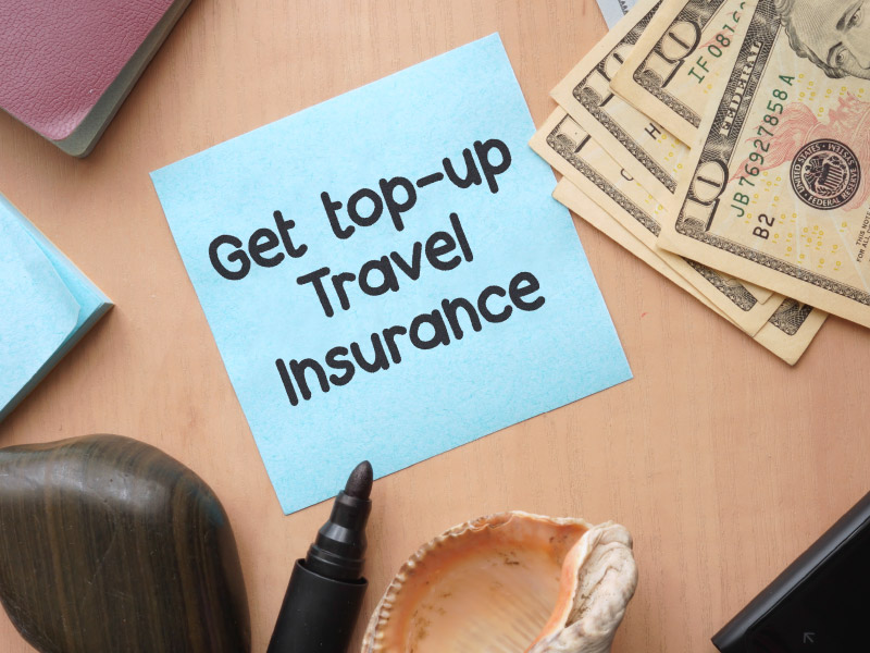 Sticky note with “get top-up travel insurance” written on it.