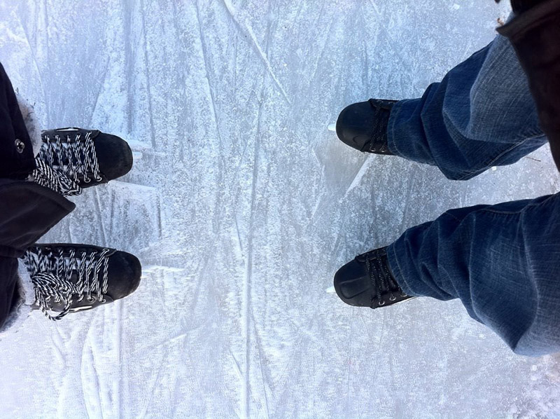 Photo of travellers’ skates on the snowy ice around the Forks in downtown Manitoba