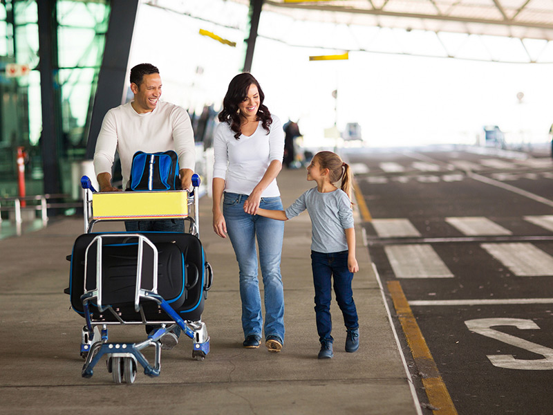Jeune famille à l’aéroport avec un chariot à bagages