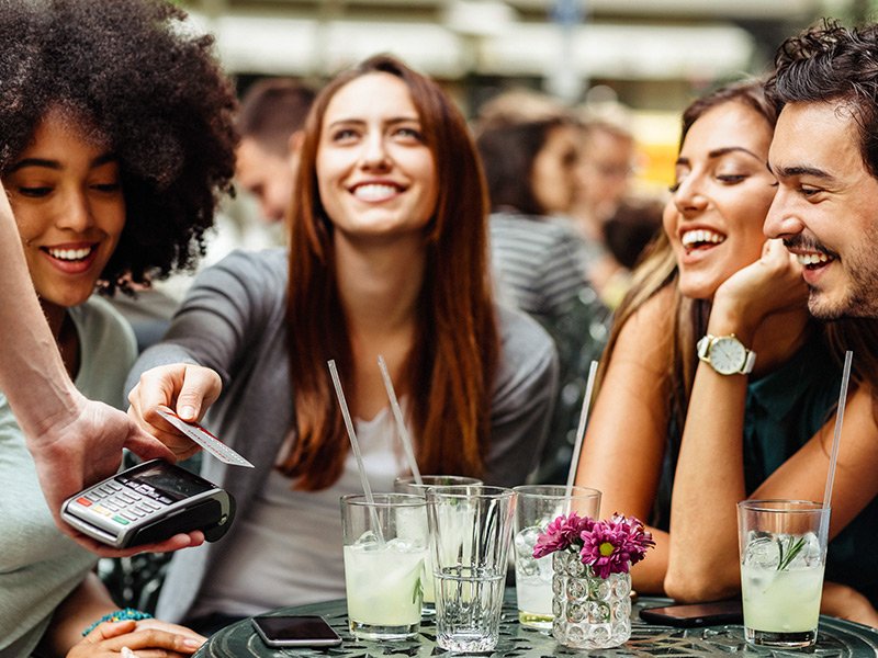 Friends paying for their bill using a credit card on vacation.