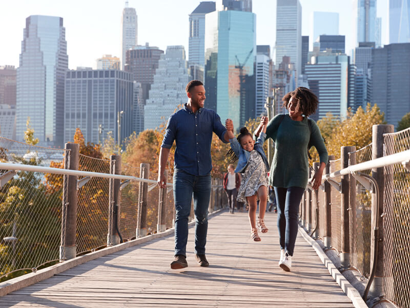 Family walks hand in hand on a footbridge in the city