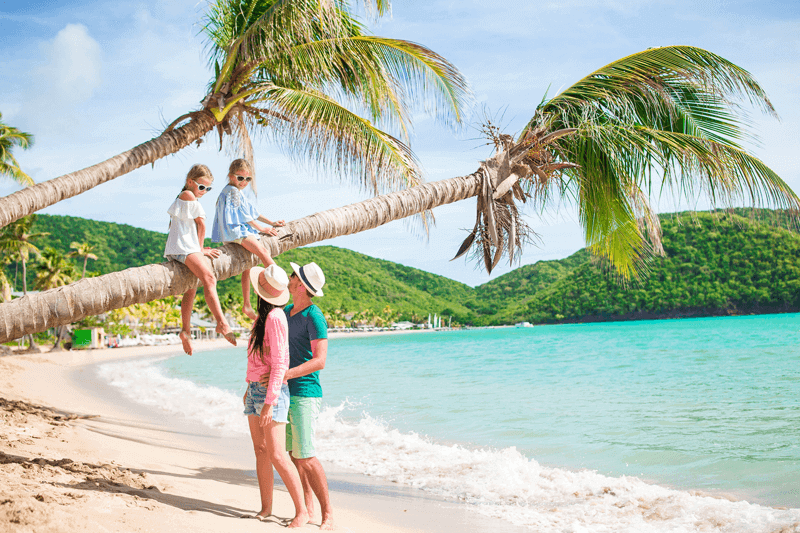 family under palm tree on tropical beach