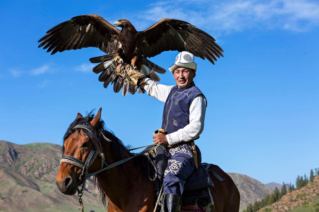 Issyk Kul, Kyrgyzstan - May 29, 2017: Golden eagle trainer holds his eagle during eagle hunter games in Issuk Kul Lake, Kyrgyzstan.