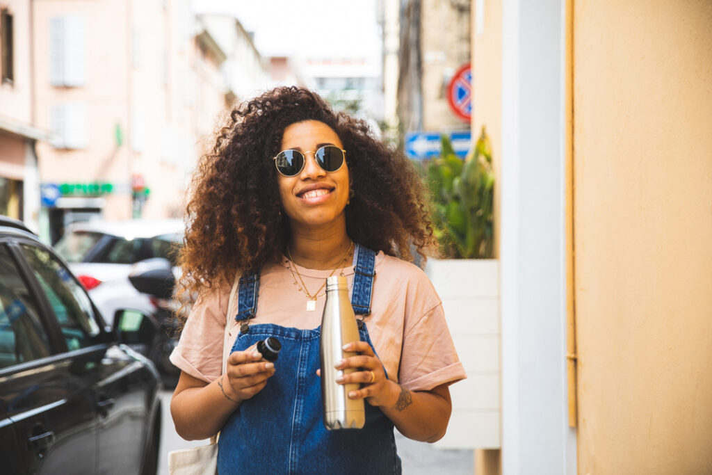 woman smiling in sunglasses with reusable water bottle