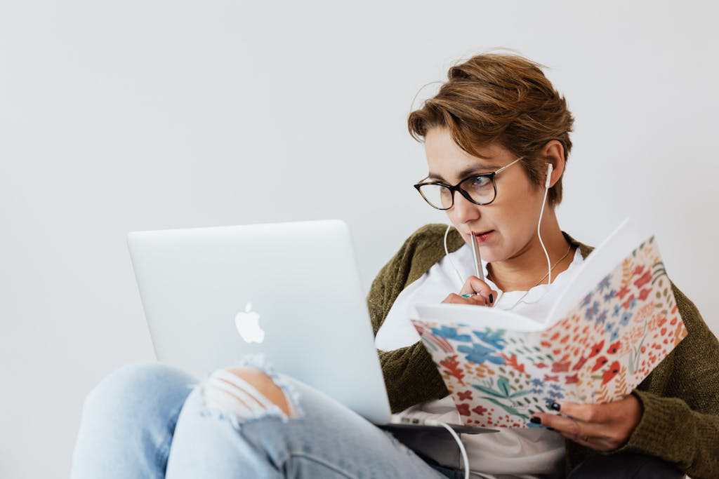 Person holding notebook and pen in front of laptop 