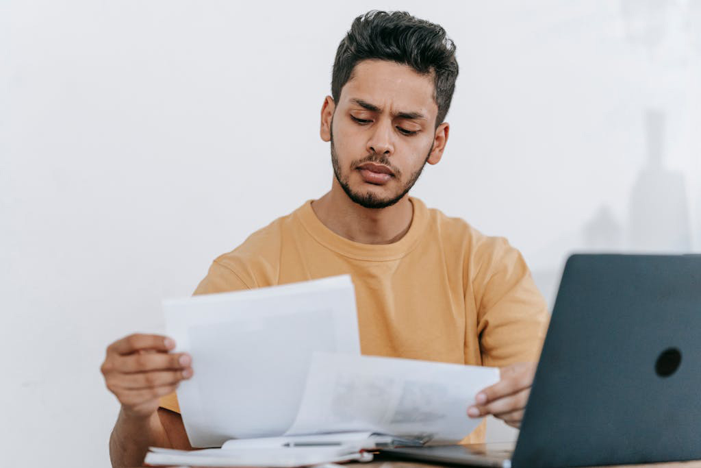 une personne avec des papiers à la main devant un ordinateur