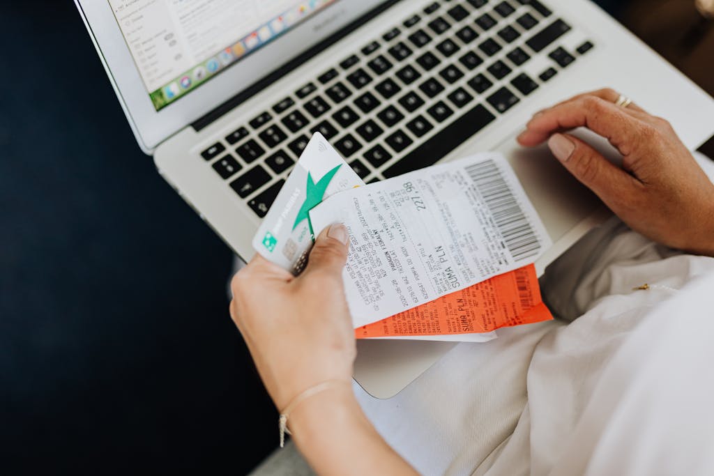 hand holding receipts in front of laptop