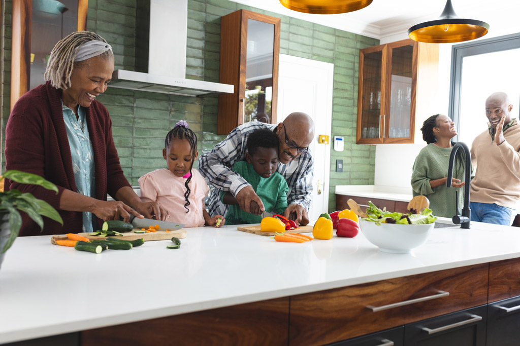 Happy African American multi generation family chopping vegetables in kitchen